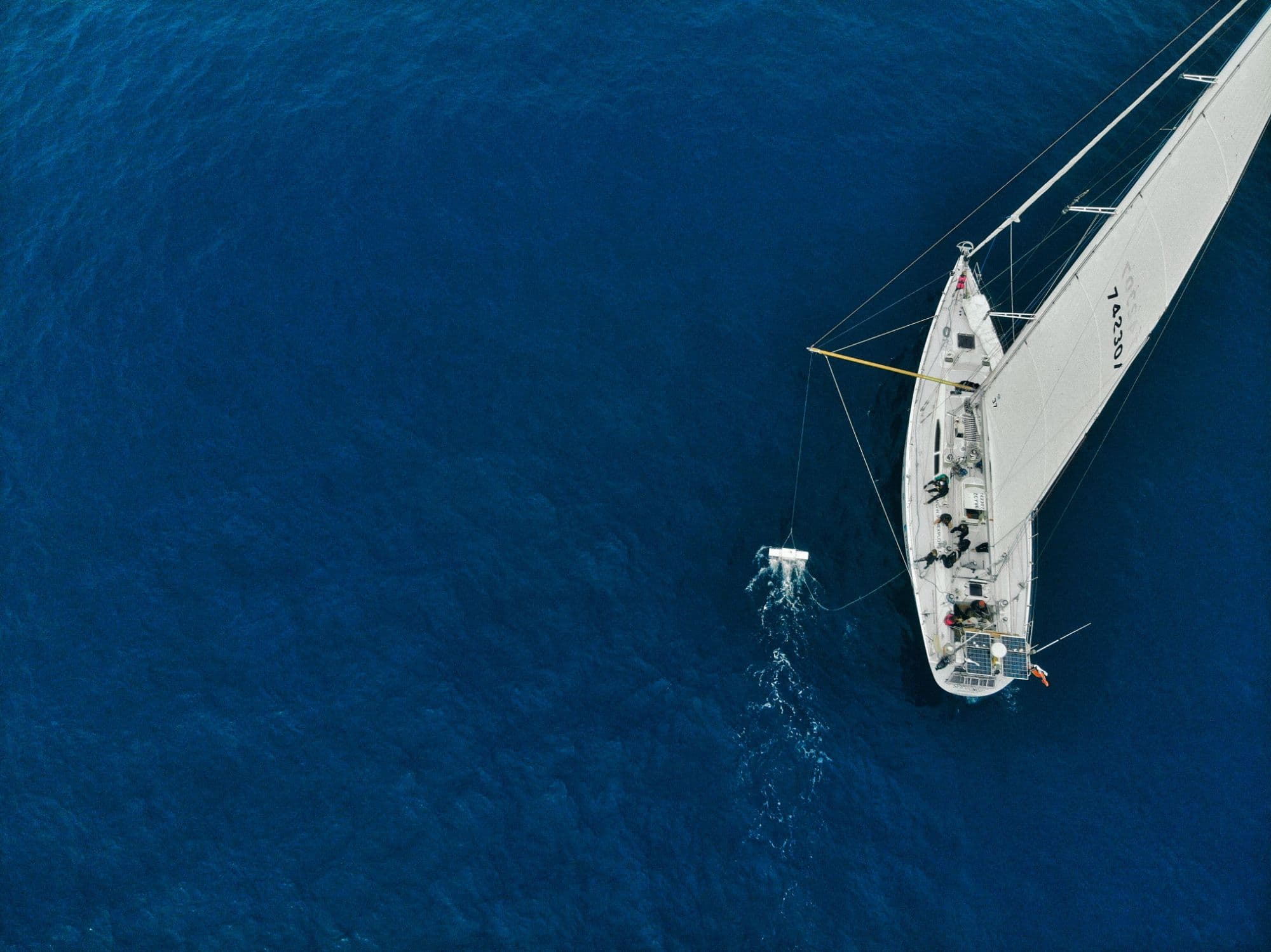 Aerial view of the eXXpedition sailing boat towing a research trawl across open ocean